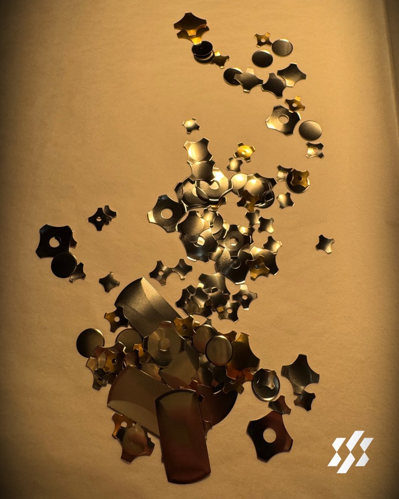 A close-up view of various metallic star-shaped and circular pieces scattered on a textured surface.