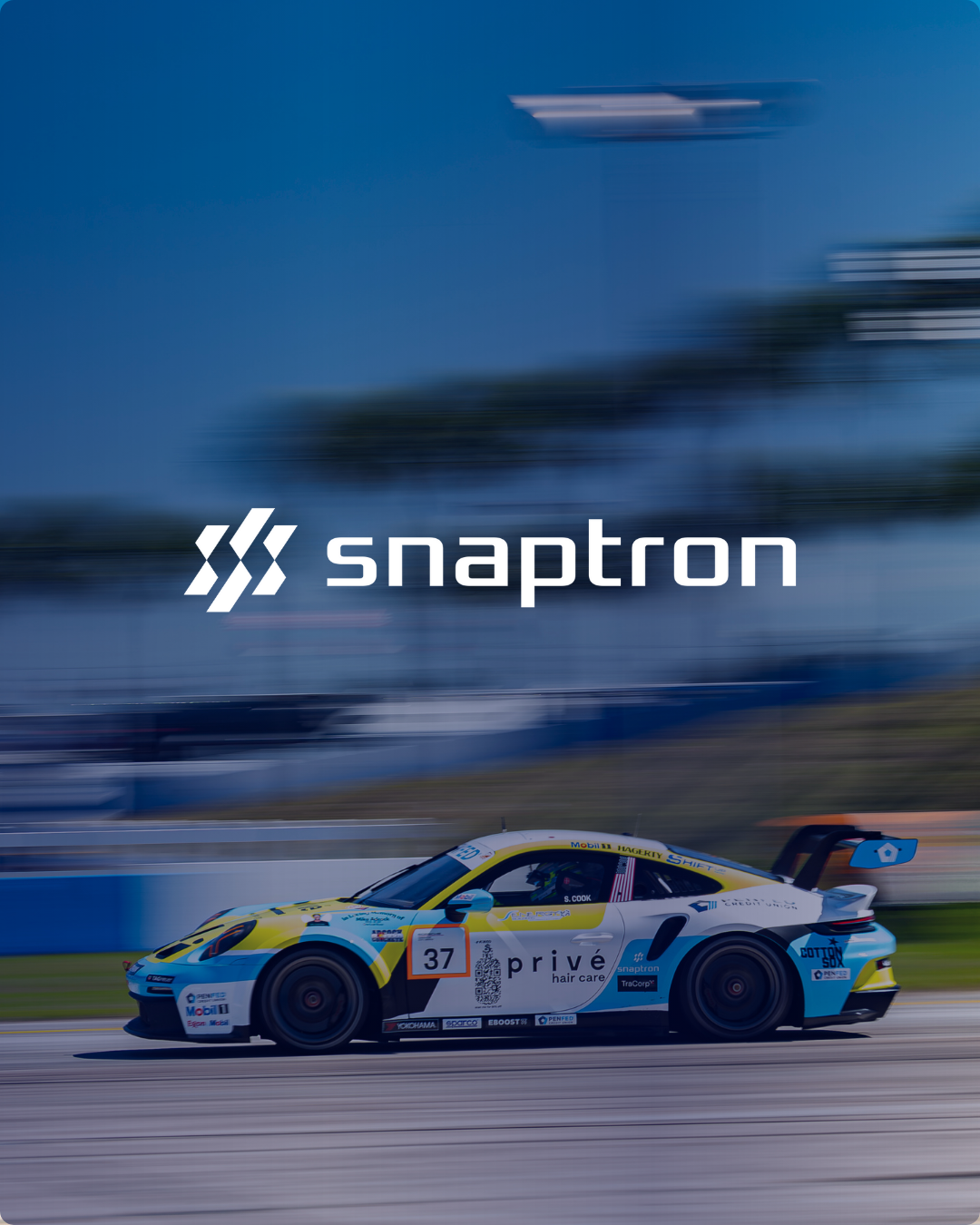 A racing car with the number 37 is speeding on a track, featuring branding for Snaptron and Privé Hair Care.
